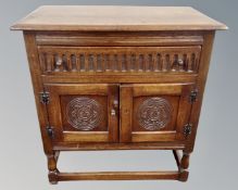 A 20th century carved double door cabinet fitted with a drawer above, on raised legs.