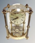 A brass German anniversary clock under dome.