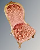 A Victorian mahogany framed lady's chair upholstered in a floral pink brocade fabric.