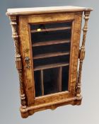 A Victorian walnut glazed door music cabinet with turned common supports.