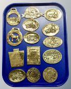 A tray containing assorted brass vintage car club plaques and horse brasses.