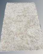 A modern cream shaggy wool rug, 140cm by 200cm.