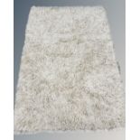 A modern cream shaggy wool rug, 140cm by 200cm.