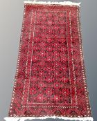 An Afghan rug on red ground, 140cm by 73cm.