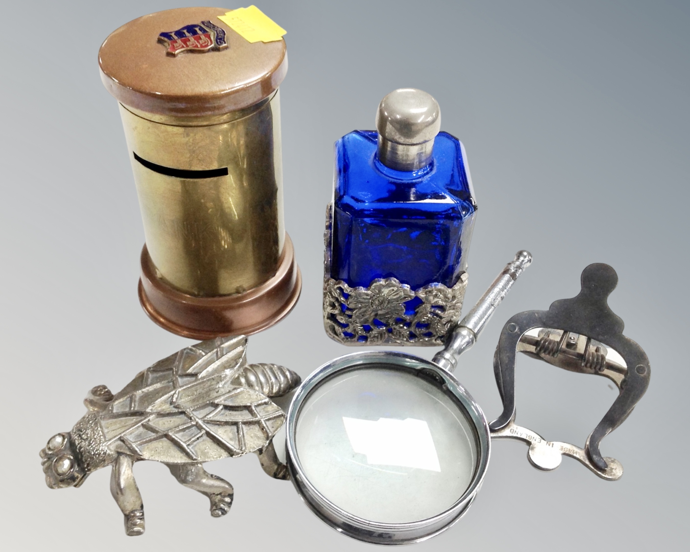 A blue glass and white metal perfume bottle together with a vintage copper and brass trench art