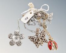 A pierced pattern flower on chain, an inlaid butterfly and a yellow metal ladybird on chain.