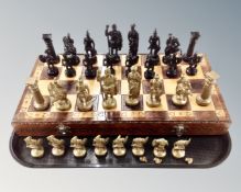 A wooden chessboard with painted metal pieces.