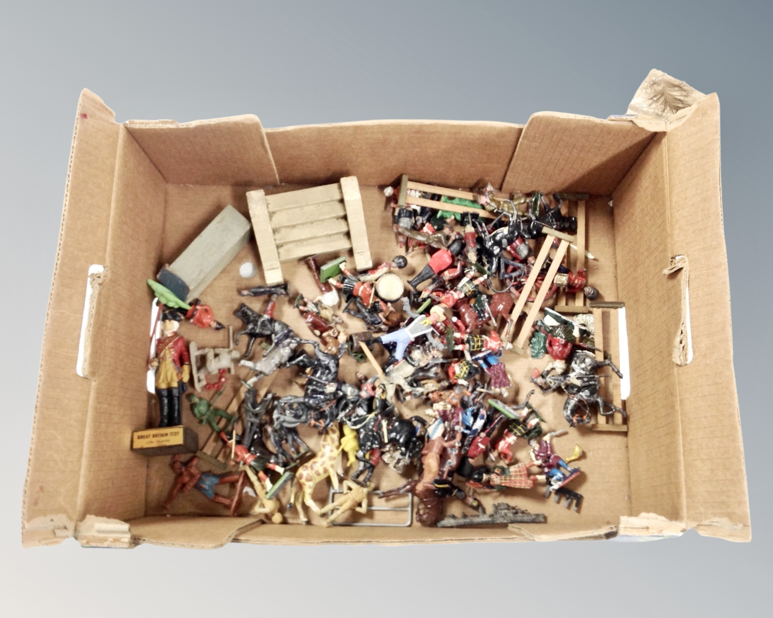 A box containing mid-20th century hand painted lead figures, plastic soldier, wooden fencing.