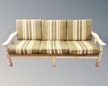 A Scandinavian three seater settee in oak frame with green striped cushions,