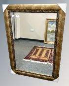 A contemporary bevelled mirror in a golden frame, 79cm by 109cm.