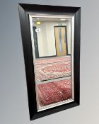 A contemporary mirror in a black frame, 51cm by 92cm.