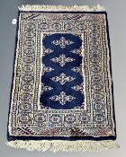 A Bokhara style rug on blue ground, 87cm by 65cm.