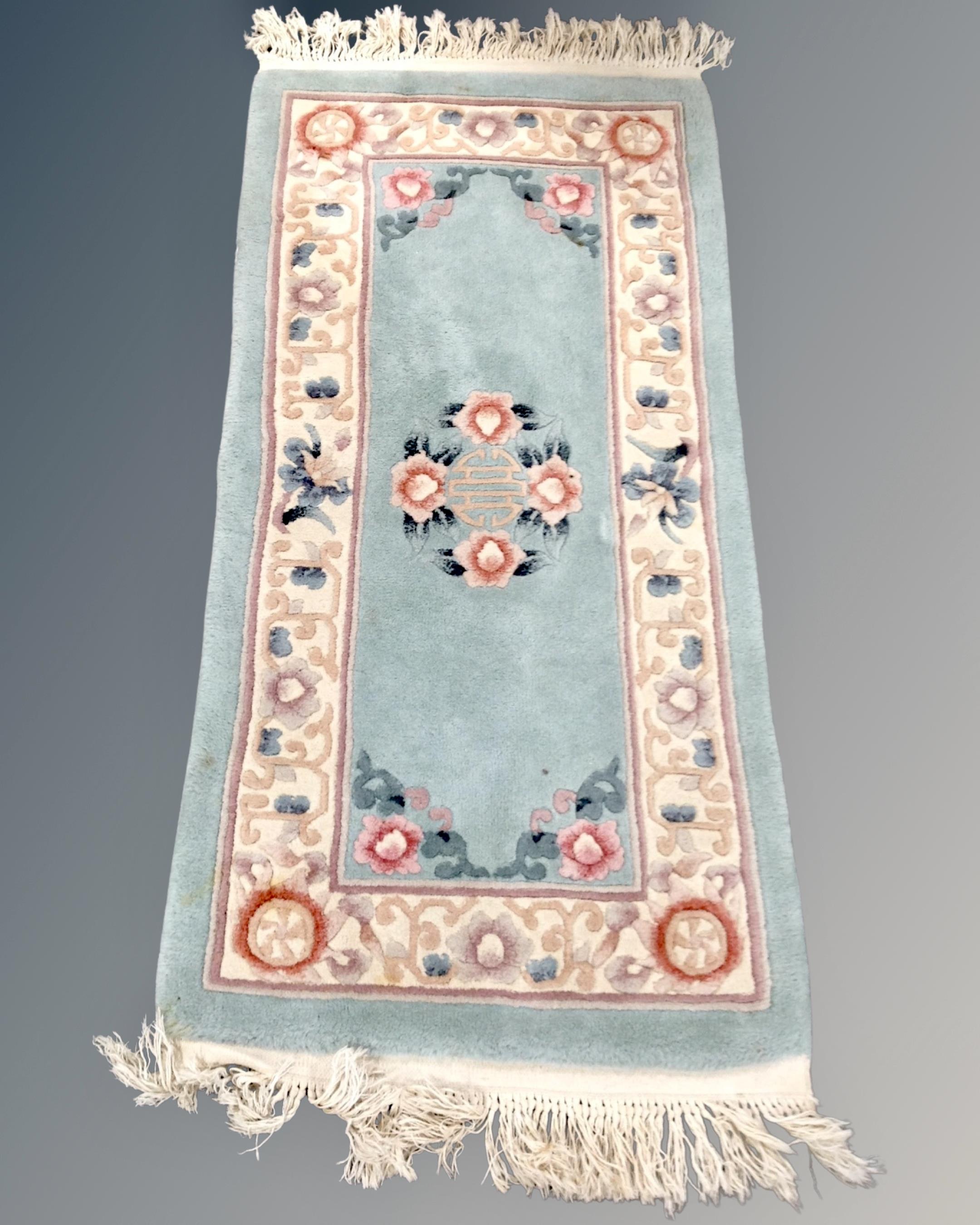 A Chinese rug on turquoise ground, 147cm by 60cm.