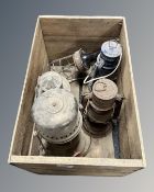 A vintage wooden crate containing three vintage oil lamps, a ship's lamp and an inspection lamp.