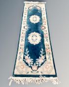 A Chinese floral patterned carpet runner on green ground, 245cm by 70cm.