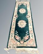 A Chinese floral patterned carpet runner on green ground, 245cm by 70cm.