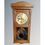 An early 20th century oak eight-day wall clock with brass dial.