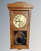 An early 20th century oak eight-day wall clock with brass dial.