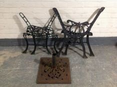 Two pairs of wrought iron bench ends and a parasol stand