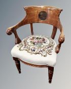 An oak elbow chair with tapestry embroidered seat and carved back.