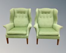 A pair of Scandinavian wingback armchairs in buttoned green upholstery.