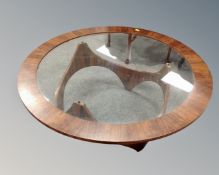 A mid 20th century circular rosewood veneered and glass topped coffee table