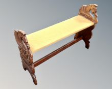 A beech piano stool with carved horse head supports.