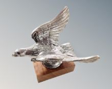 An eagle car mascot, mounted on a wooden plinth.
