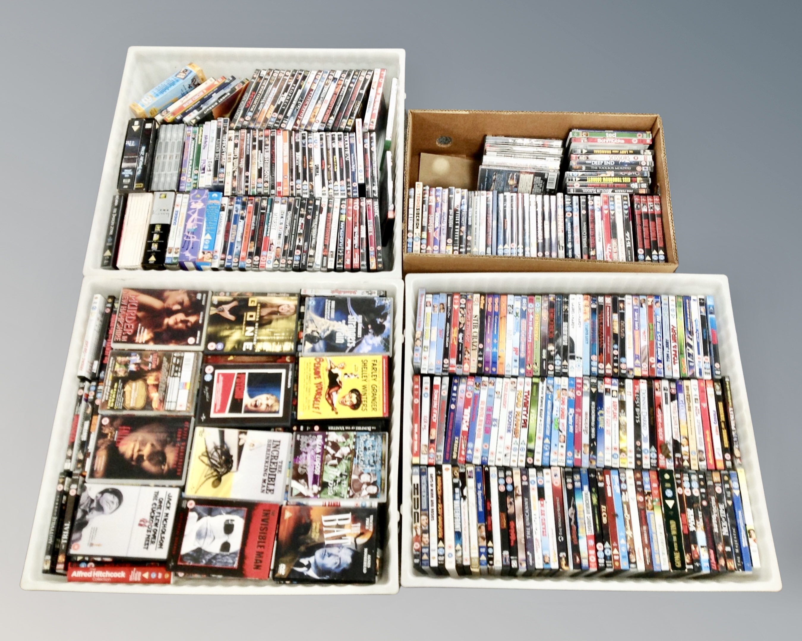 A box and three plastic crates containing a large quantity of DVD movies and box sets.
