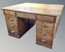 A 1930s oak twin pedestal writing desk fitted with nine drawers.