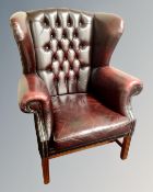 A Chesterfield oxblood buttoned leather wingback armchair.