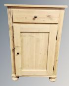 A pine single door side cabinet fitted with a drawer.