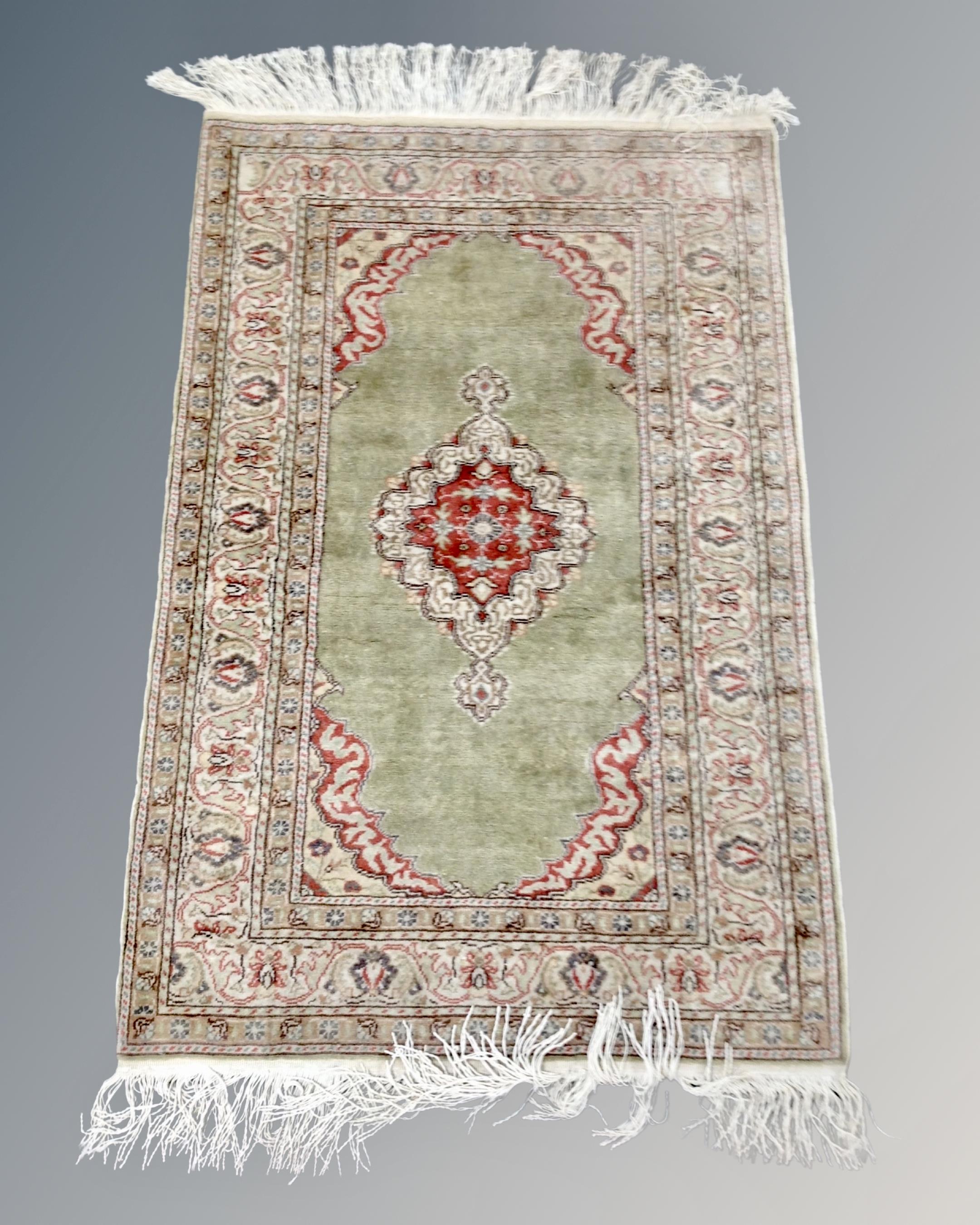 A Turkish Anatolian fringed rug on green ground, 150cm by 87cm.