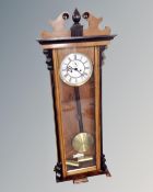 A Continental walnut and ebonized Vienna style eight-day wall clock with white enamelled dial.