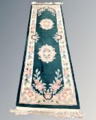 A Chinese floral patterned carpet runner on green ground, 245cm by 70cm.