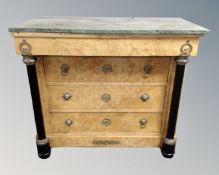 A green marble topped satinwood veneered empire style chest of three drawers,
