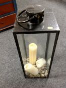 A hurricane lamp containing stones and candles