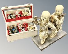 A musical jewellery box containing costume jewellery together with a Chinese resin figure.