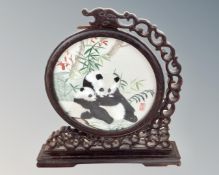 A Chinese embroidered table screen depicting pandas on a carved hardwood fretwork stand,