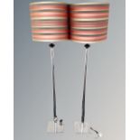 A pair of contemporary chrome floor lamps with shades