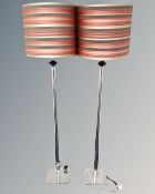 A pair of contemporary chrome floor lamps with shades