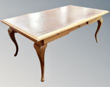 A 20th century library table fitted with three drawers on with tooled leather top
