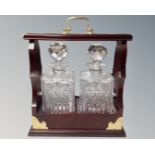 A two bottle Tantalus with key containing two lead crystal whisky decanters.