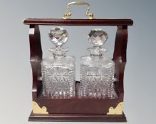 A two bottle Tantalus with key containing two lead crystal whisky decanters.