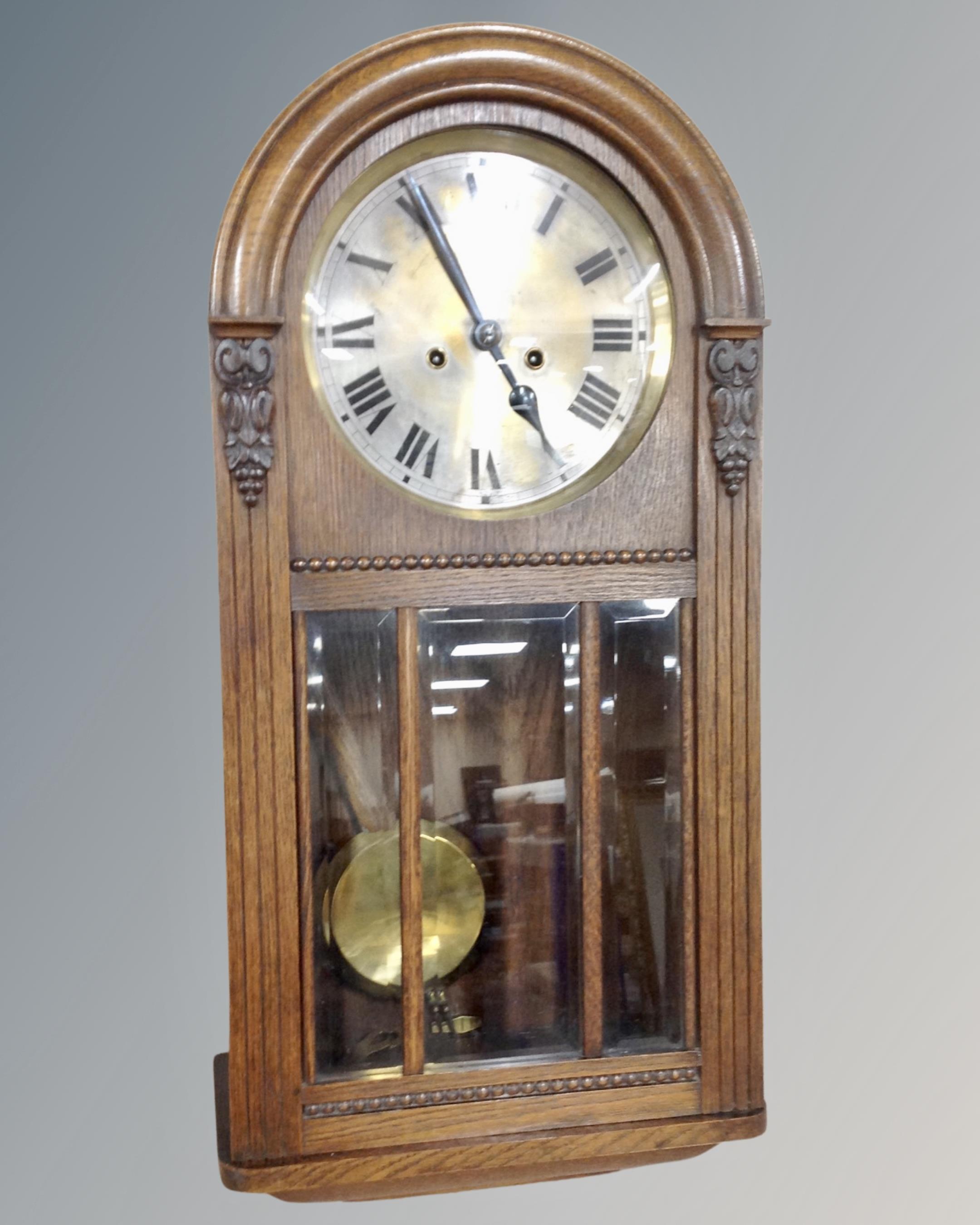 An Edwardian oak cased dome top wall clock with silvered dial,