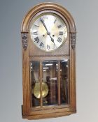 An Edwardian oak cased dome top wall clock with silvered dial,