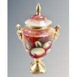 A Coalport hand painted and gilt lidded urn, decorated with panels of fruit by N.B.