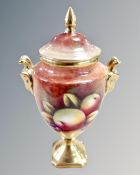 A Coalport hand painted and gilt lidded urn, decorated with panels of fruit by N.B.
