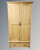 A contemporary oak double door wardrobe fitted with a drawer