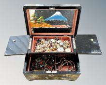 A lacquered musical jewellery box containing costume jewellery
